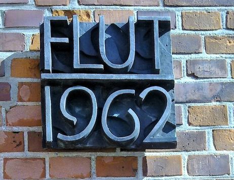 Gedenktafel zur Flut 1962 an einer Backsteinmauer.