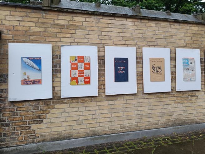 Plakate von Buchcovern an einer Backsteinmauer, Teil einer Ausstellung über Bücherverbrennungen 1933.