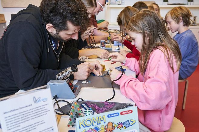 Mehrere Kinder, die mit dem Lötkolben Sachen reparieren