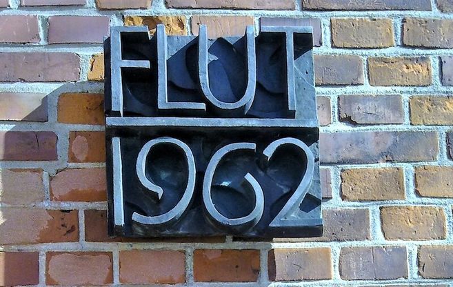 Gedenktafel zur Flut 1962 an einer Backsteinmauer.