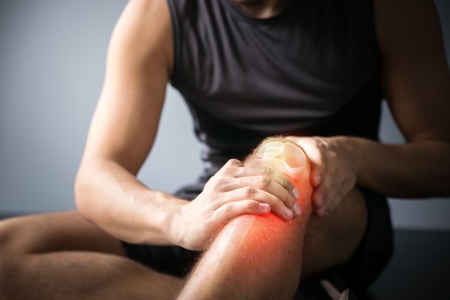 Ein Mann hält sich das Knie.