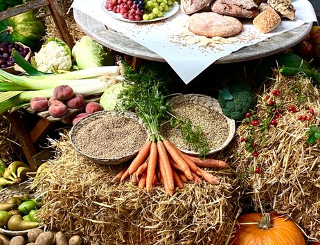 Ein Erntedankaltar mit Brot, Trauben, Gemüse und Getreide auf Strohballen dekoriert.