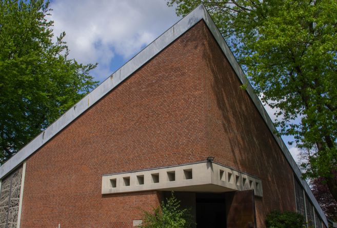 Backsteingebäude mit modernem Design und Bäumen im Hintergrund.