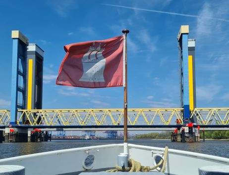 Am Bug eines Schiffs flattert eine Hamburg-Fahne, während das Schiff auf die Kattwykbrücken zusteuert.