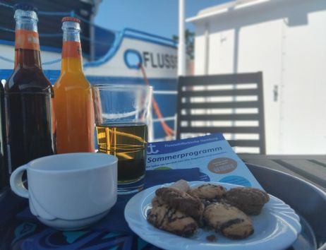 Ein Kaffee- und Kuchengedeck mit Softdrinks auf dem sommerlichen Ponton der Flussschifferkirche Hamburg.