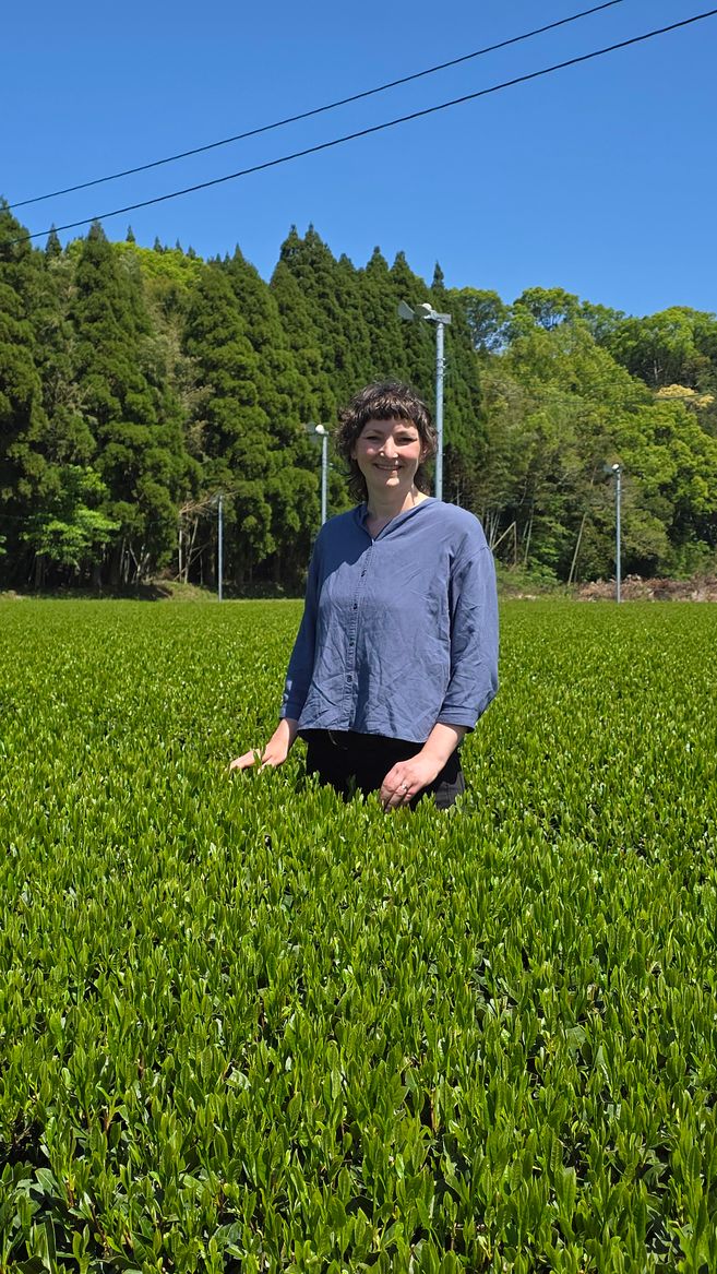 Tee-Expertin Marieke Wege steht in einem Teefeld in Kagoshima, über ihr der blaue Himmel