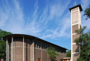 Moderne Kirche mit hohem Turm und blauer Himmel im Hintergrund.