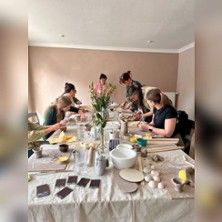 Menschen bei einem Keramik-Workshop an einem Tisch mit Töpfermaterialien.