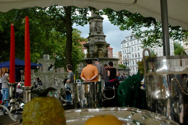 Flohmarktstand und Brunnen im Hintergrund mit Bäumen
