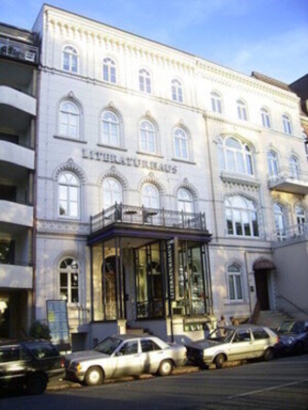 Fassade des Literaturhauses mit geparkten Autos davor.