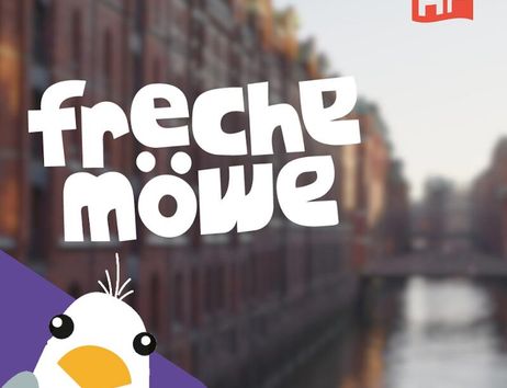 Illustration einer Möwe mit dem Text 'freche möwe' vor einem unscharfen Hintergrund einer Stadt mit Wasserkanal.