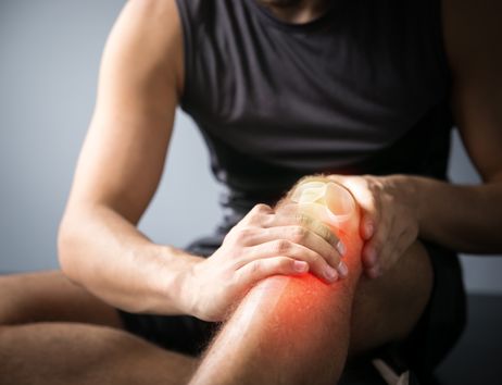Ein Mann hält sich das Knie.