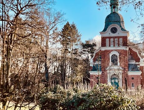 Eine historische Backsteinkirche mit Turm, umgeben von Bäumen im Luthergarten.