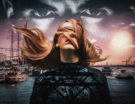 Eine Frau mit wehenden Haaren steht vor einem Hafen bei Sonnenuntergang, über ihr ein großes, geheimnisvolles Augenpaar am Himmel. Die Stimmung ist düster und emotional.