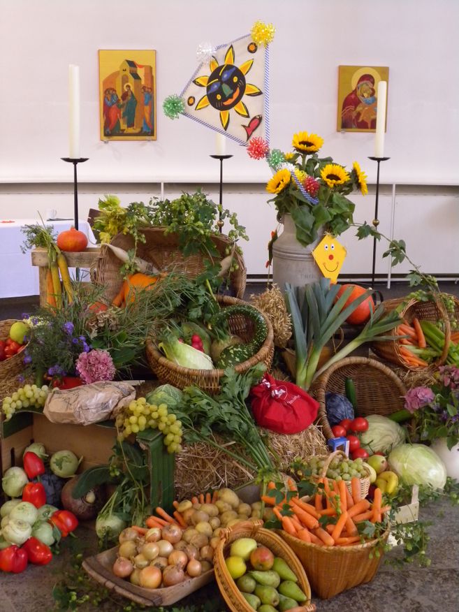 Erntedankfest mit reich geschmücktem Altar, Sonnenblumen, Kerzen, Ikonen und vielen Körben voller Obst, Gemüse und Getreide.