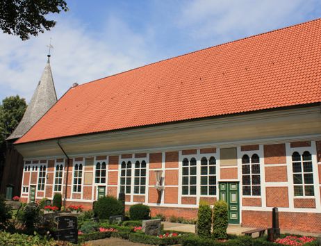 Außenansicht der Dreieinigkeitskirche in Allermöhe mit rotem Ziegeldach und Fachwerkfassade.
