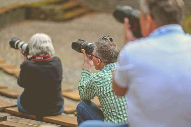 Drei Personen mit Kameras bei einem Fotoworkshop im Freien.