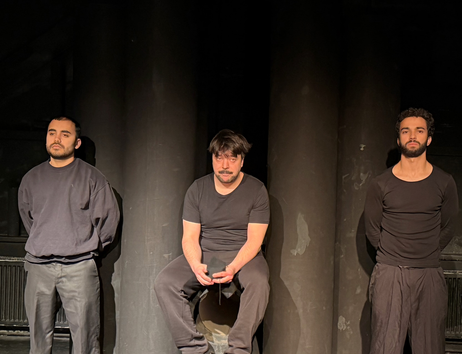 Es sind Drei Männer abgebildet, der in der Mitte sitzt auf einem Rohr, während die anderen zwei zu seiner Seite Wache stehen. von links nach rechts: Quentin Barich als Wache 1, Emrah Demir als Sipan und Marlon Mähnert als Wache 2