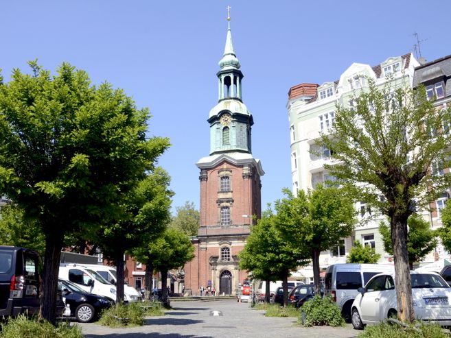 Dreieinigkeitskirche St. Georg mit Bäumen und Autos im Vordergrund.
