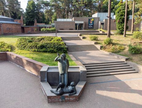 Außenansicht des Museums mit Skulptur im Vordergrund und Treppen zum Eingang.