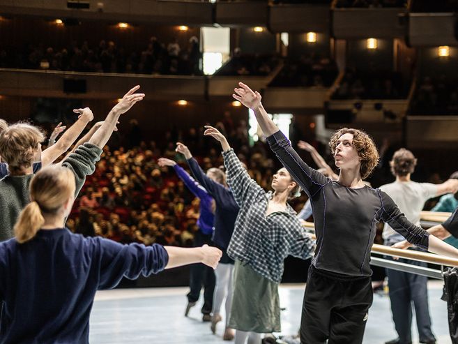 Balletttänzer üben auf einer Bühne vor Publikum.