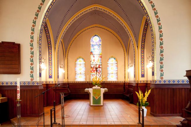 Innenraum der Martinskirche mit Altar, farbigen Spitzbogenfenstern, Gewölbe und Blumenarrangements; kein Gottesdienstbesuch zu sehen.