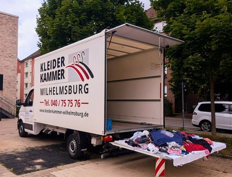 Ein geöffneter Lieferwagen der Kleiderkammer Wilhelmsburg mit Kleidung auf der Ladefläche.