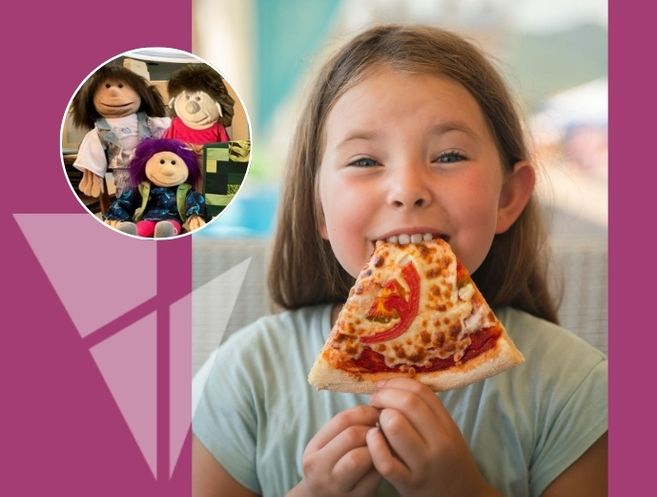 Ein Mädchen isst ein Stück Pizza. Im Hintergrund sind drei Puppen zu sehen.