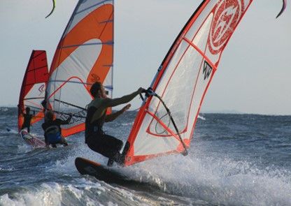 Drei Windsurfer fahren bei starkem Wind auf dem Meer.
