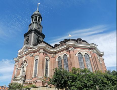 Die St. Michaelis Kirche in Hamburg mit ihrem markanten Turm und der barocken Fassade vor einem blauen Himmel.