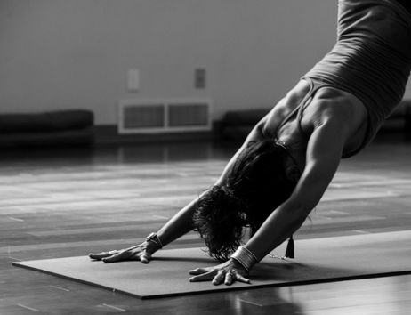 Eine Person praktiziert eine Yoga-Pose auf einer Matte in einem Raum.