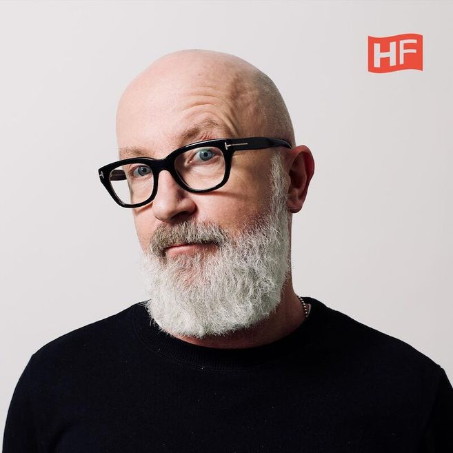 Porträt eines Mannes mit Brille und weißem Bart vor einem neutralen Hintergrund mit HF-Logo.