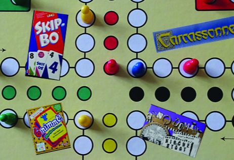 Spielbrett mit Spielfiguren und Karten von Skip-Bo, Carcassonne, 6 nimmt! und Dominion.