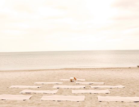Yoga-Matten auf einem sandigen Strand mit Blick auf das Meer.