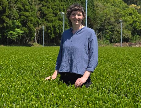 Tee-Expertin Marieke Wege steht in einem Teefeld in Kagoshima, über ihr der blaue Himmel