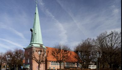 Kirche St. Johannis in Hamburg-Eppendorf mit spitzem Turm und rotem Ziegeldach.