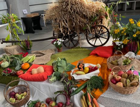Erntedankfest-Dekoration mit Obst, Gemüse und einem Heuwagen in einer Kirche.