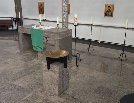 Innenansicht einer Kirche mit Altar, Kerzenständern und Ikonen an der Wand.